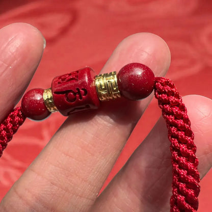 Red beaded bracelet with gold accents held between fingers against a red background
