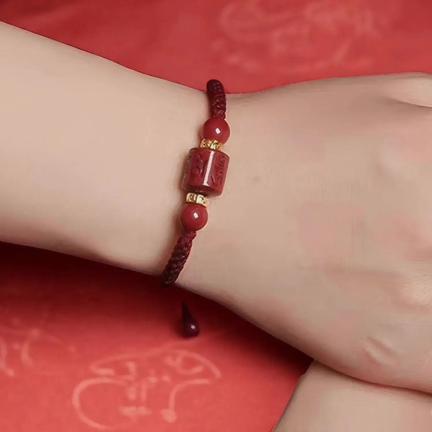 Red beaded bracelet on a wrist with a red background