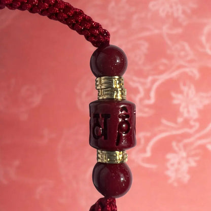 Red beaded keychain with gold accents on a pink floral background