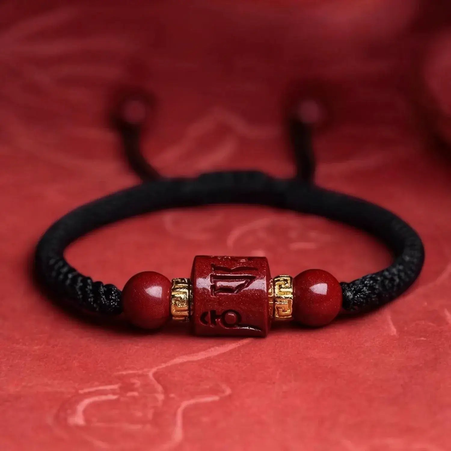 Black braided bracelet with red beads and a gold accent on a red background