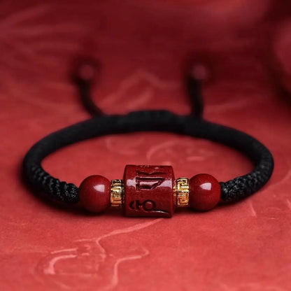 Black braided bracelet with red beads and a gold accent on a red background
