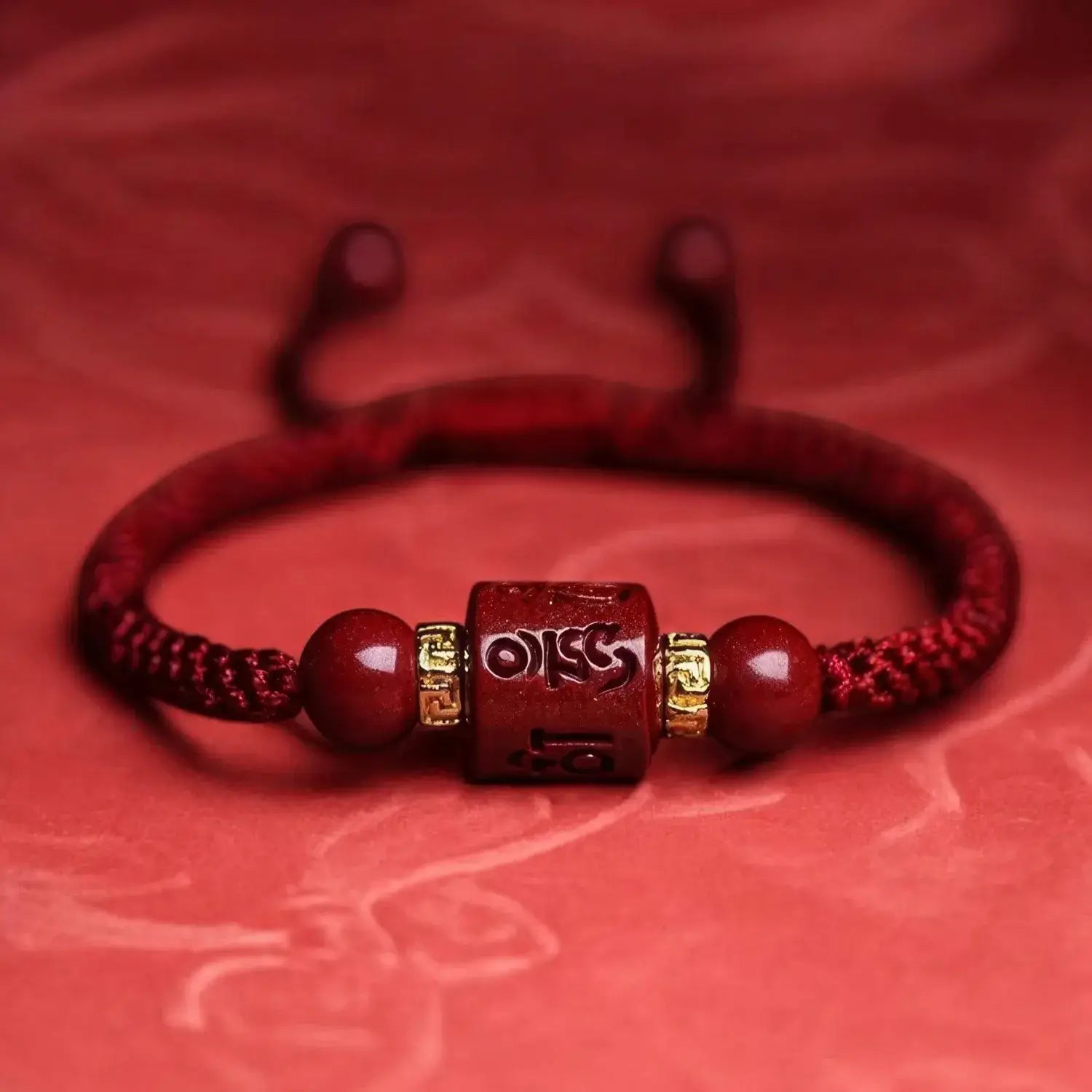 Red bracelet with a central bead and 'OM' symbol on a red background