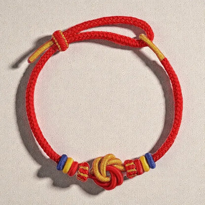 Red cord bracelet with colorful beads and knot on a light gray background