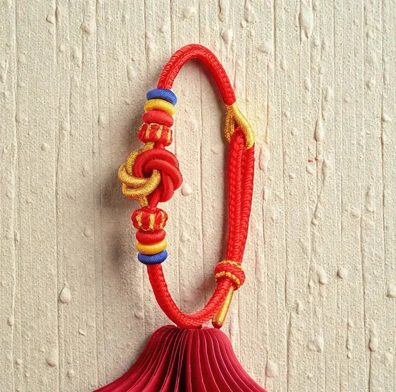 Colorful decorative tassel with red rope on a textured beige background