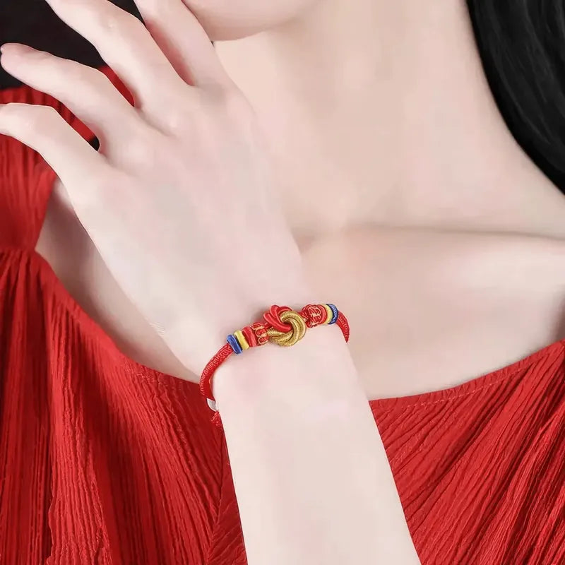 Close-up of a hand wearing a colorful bracelet on a red dress.