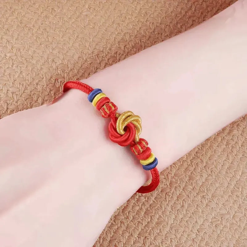 Red bracelet with colorful knots on a wrist against a beige background