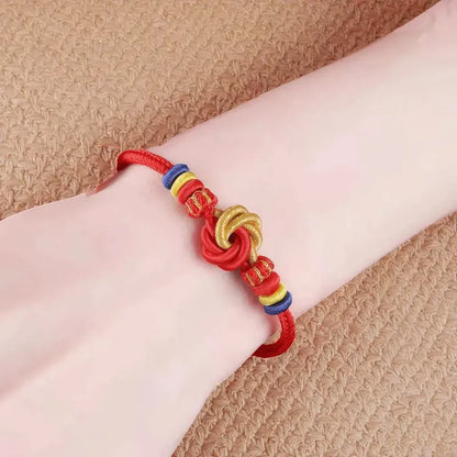 Red bracelet with colorful knots on a wrist against a beige background