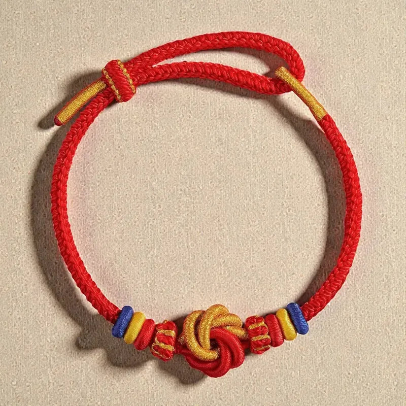 Red bracelet with colorful knots and beads on a beige background