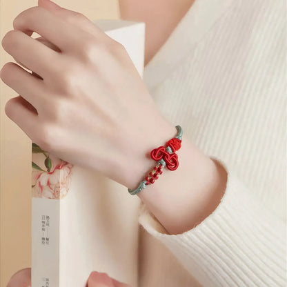 Hand wearing a red and green bracelet on a light background