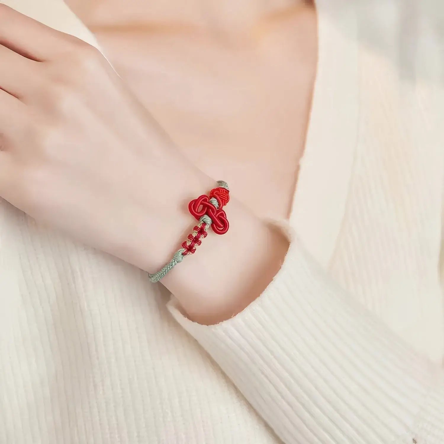 Red bracelet with a silver clasp on a wrist against a white background