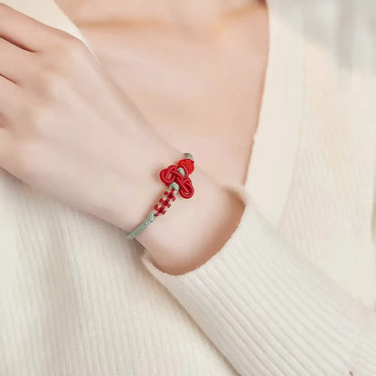Red bracelet with a silver clasp on a wrist against a white background