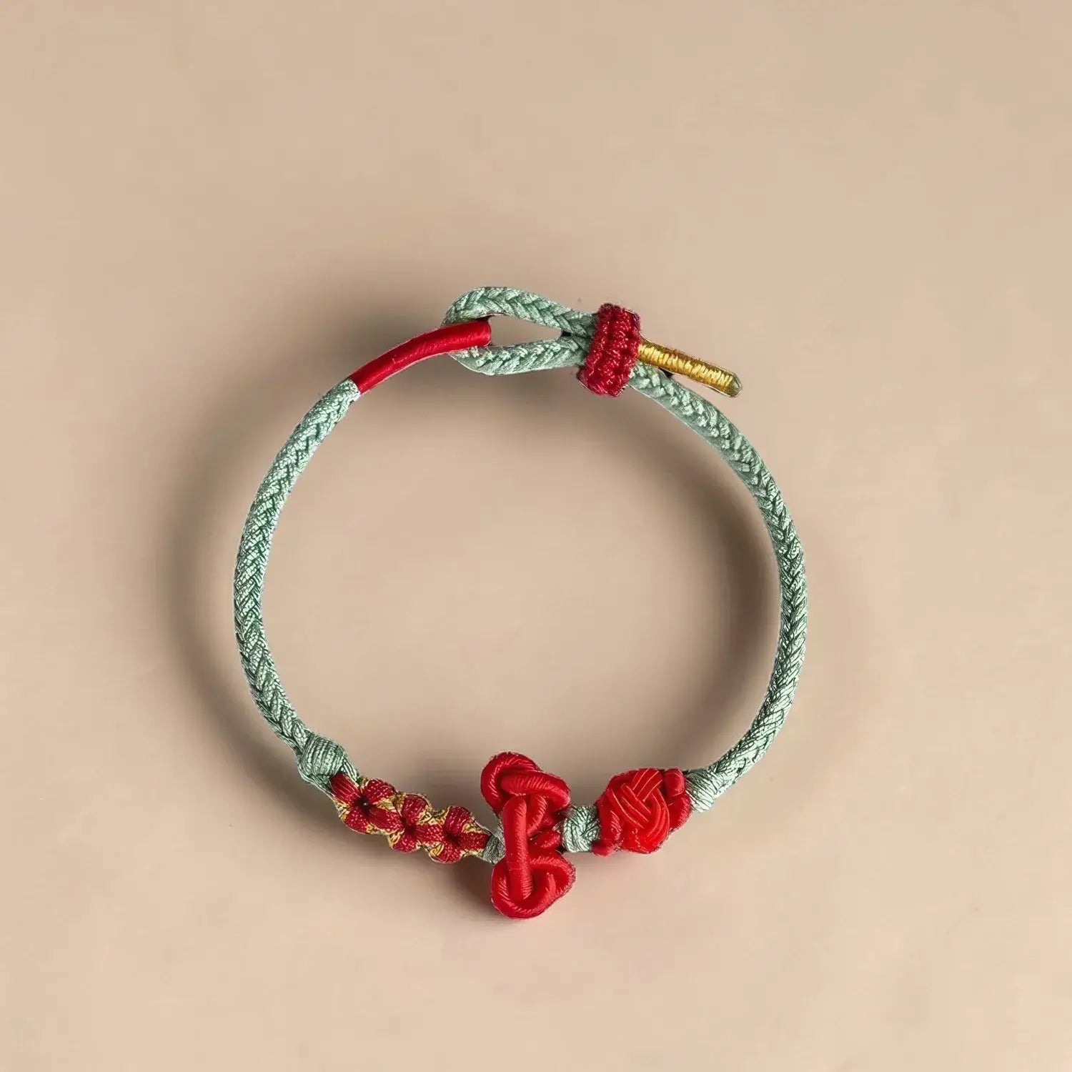 Bracelet with red and gold accents on a beige background