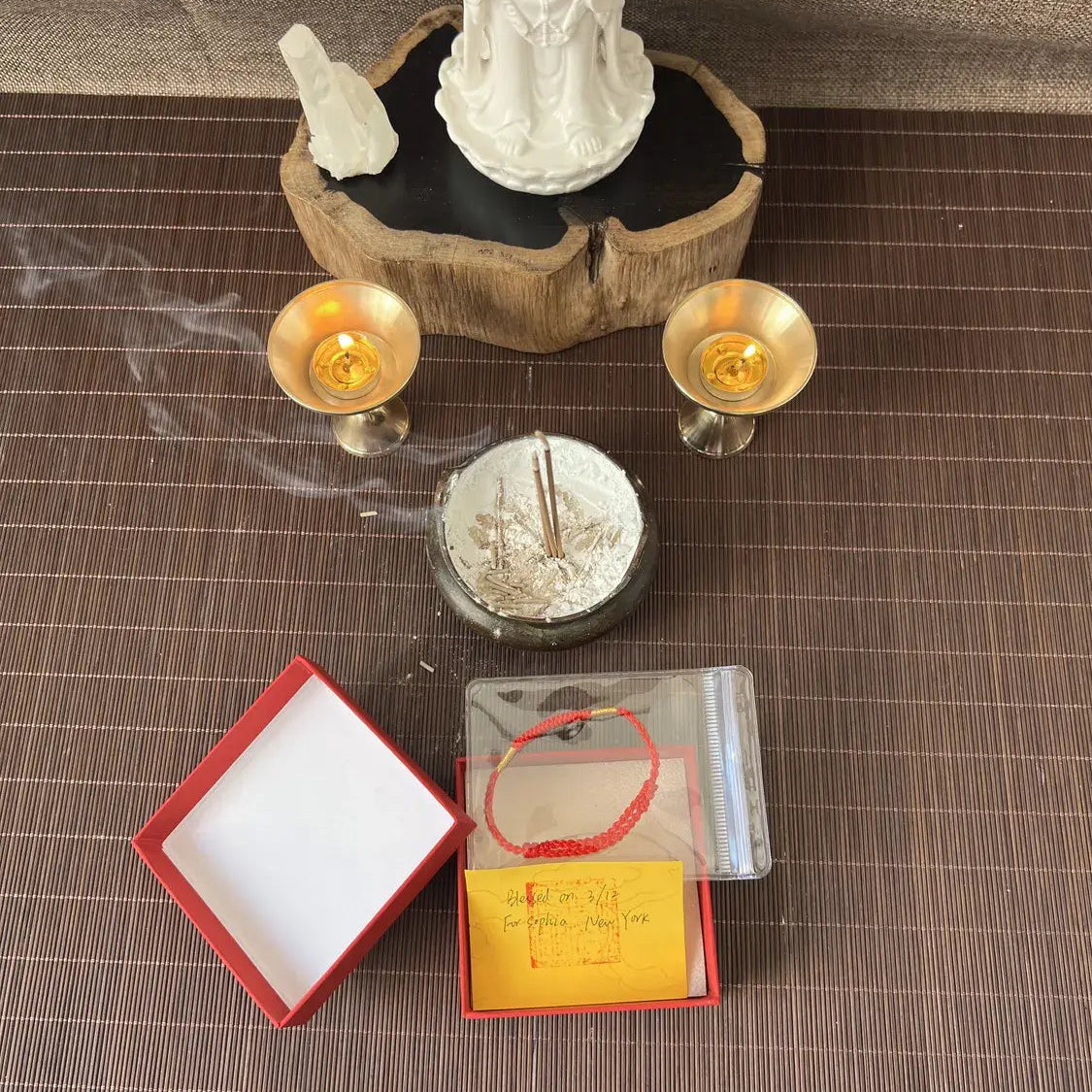 Incense sticks with smoke, a statue, and a box on a textured surface