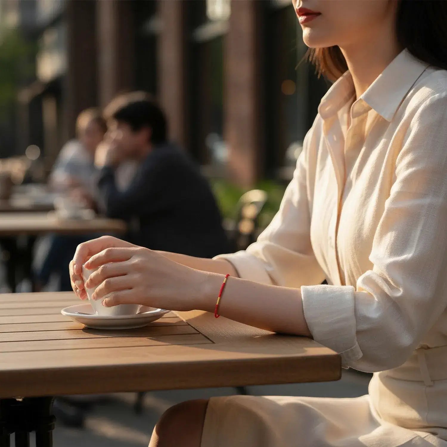 Woman sitting at an outdoor cafe table with a blurred background