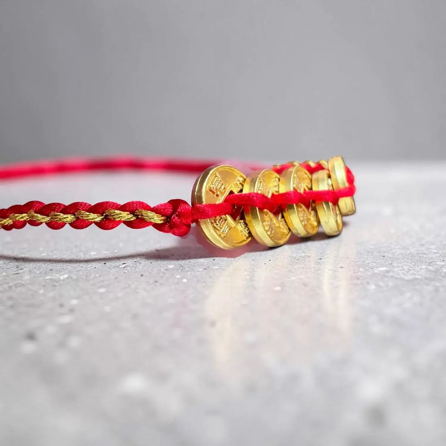 Gold coins on a red string against a gray background