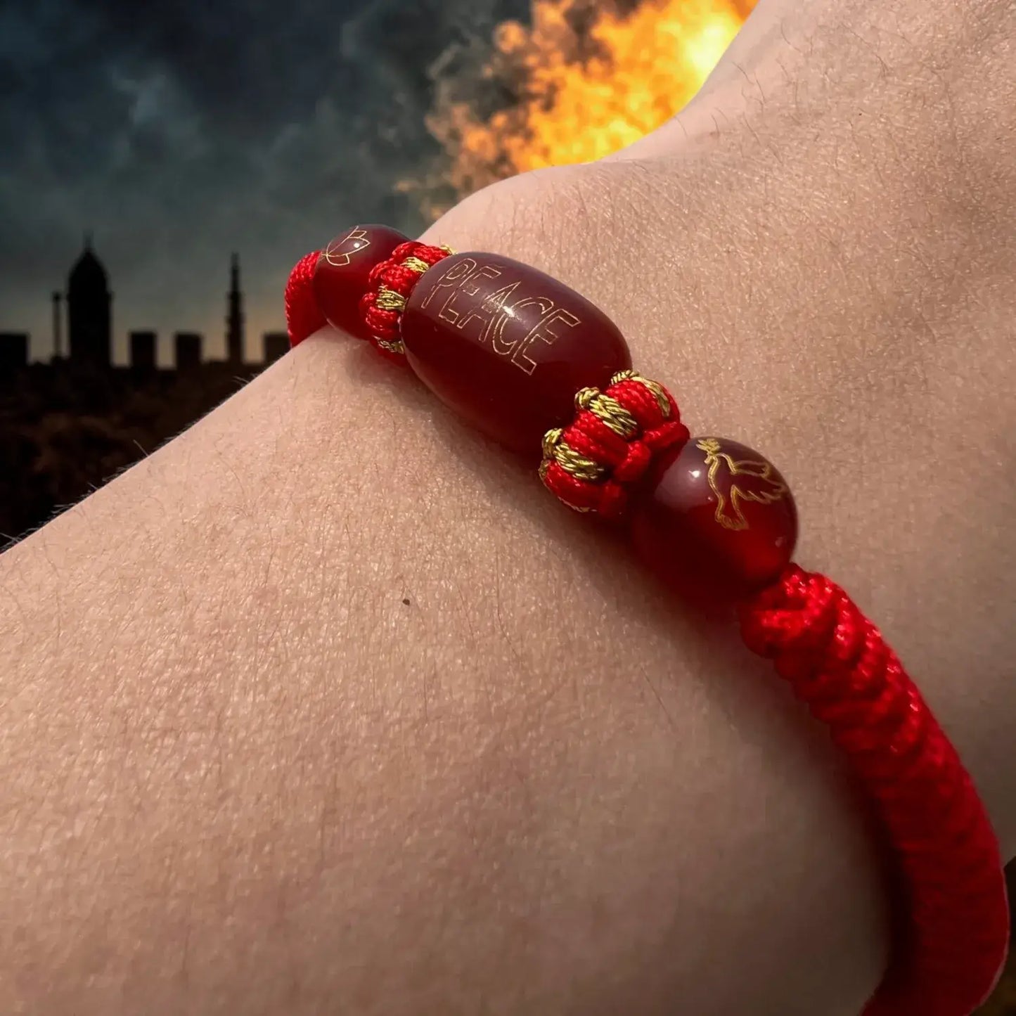 Red bracelet with gold accents on a wrist against a cityscape background