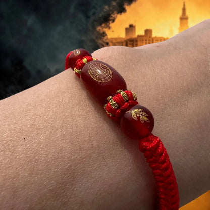 Red and gold bracelet on a wrist with a cityscape in the background