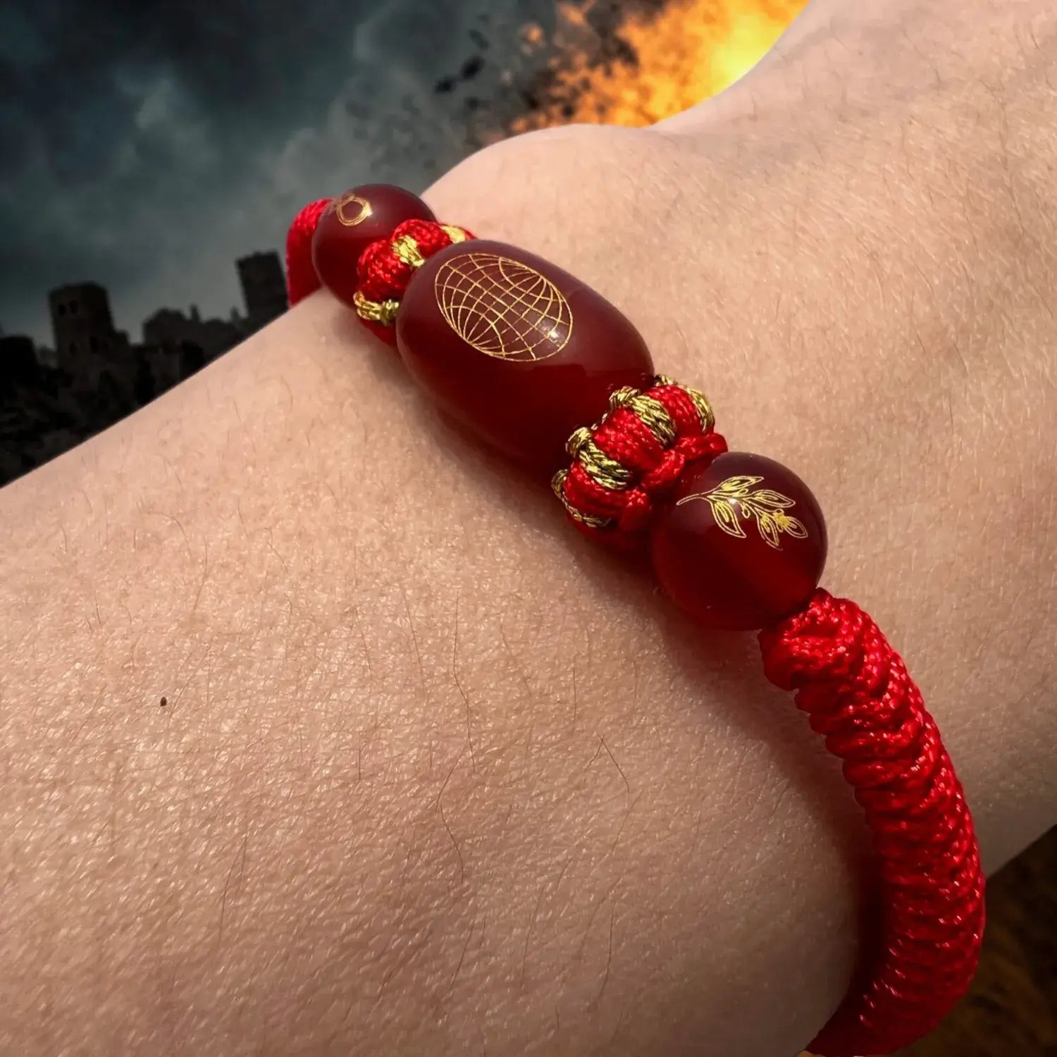 Red beaded bracelet with gold accents on a wrist against a dark background