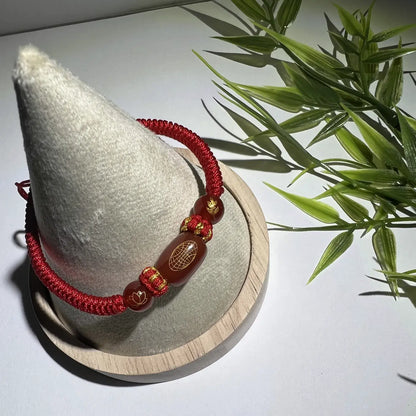 Red beaded bracelet on a cone-shaped display with a plant in the background