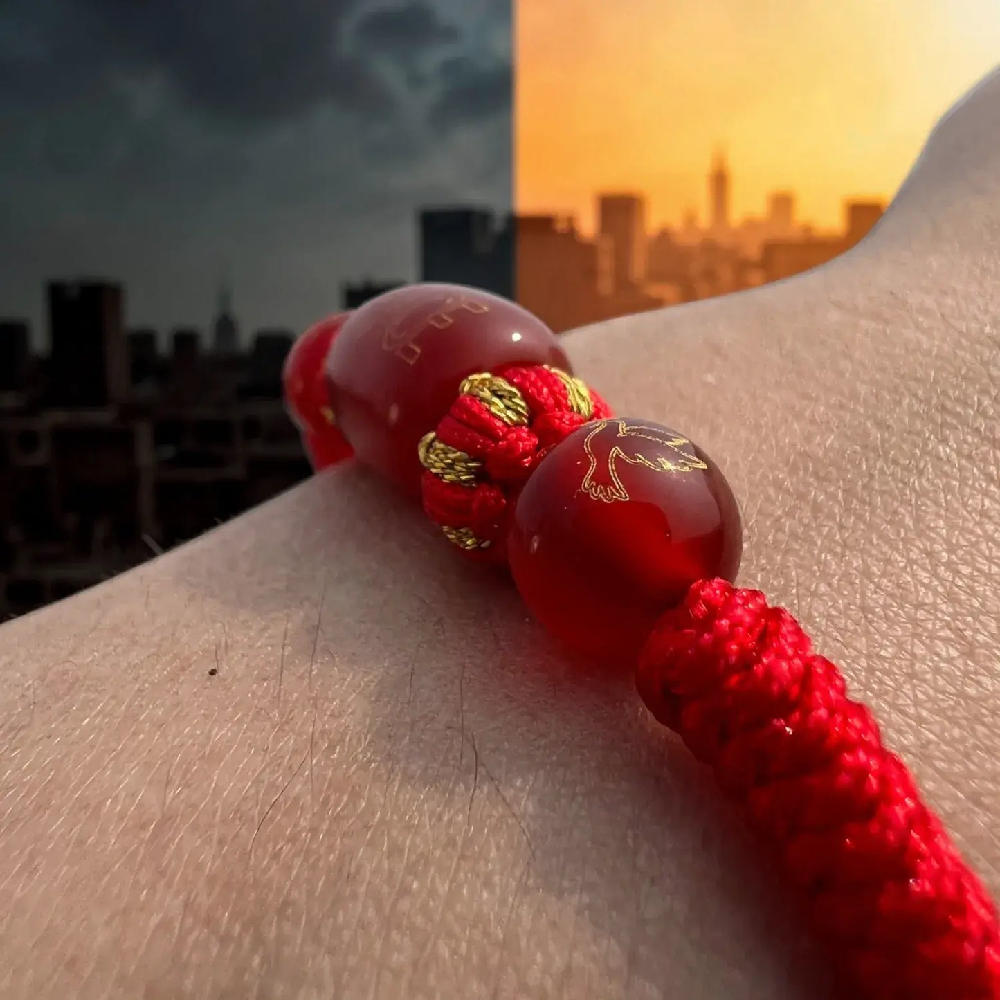 Red beaded bracelet on a wrist with a cityscape background