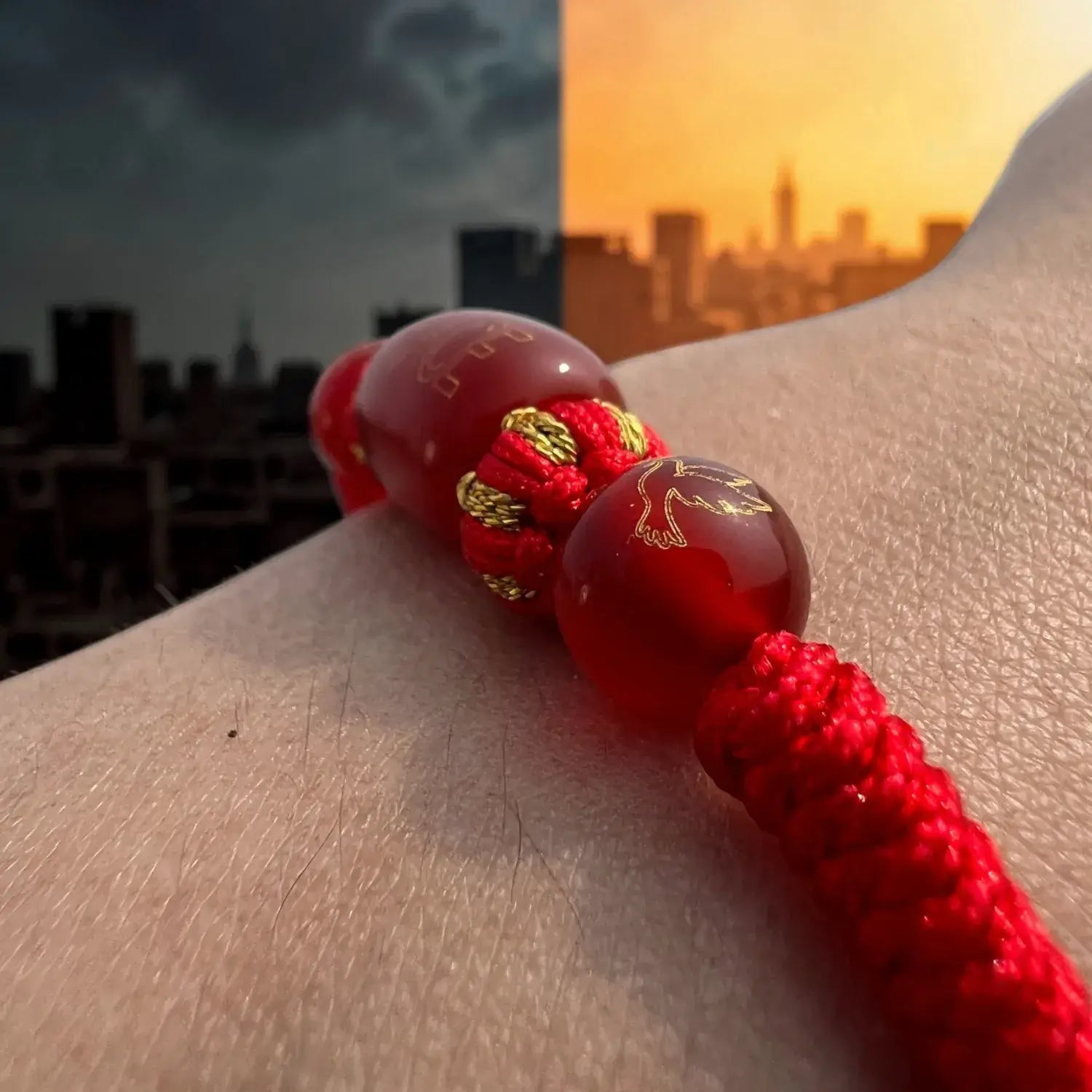 Red beaded bracelet on a wrist with a cityscape background